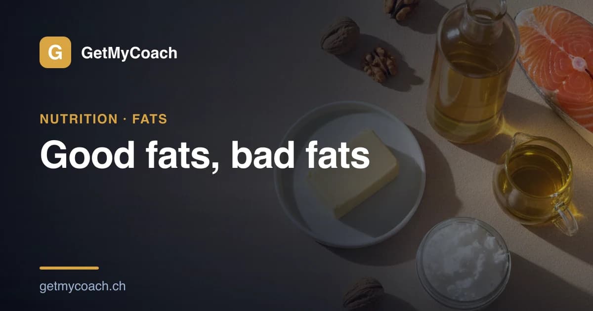 A dark kitchen surface with a glass bottle of golden rapeseed oil, a small jug of olive oil, a block of butter on a plate, an open jar of solid white coconut fat, scattered walnuts and a salmon steak — cover image for the GetMyCoach guide to good and bad fats.