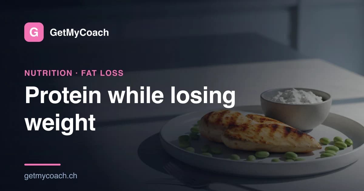 A white plate on a dark kitchen counter in low, soft light, holding a grilled chicken breast surrounded by green edamame beans, with a small bowl of white quark beside it — cover image for the GetMyCoach guide to protein during weight loss.
